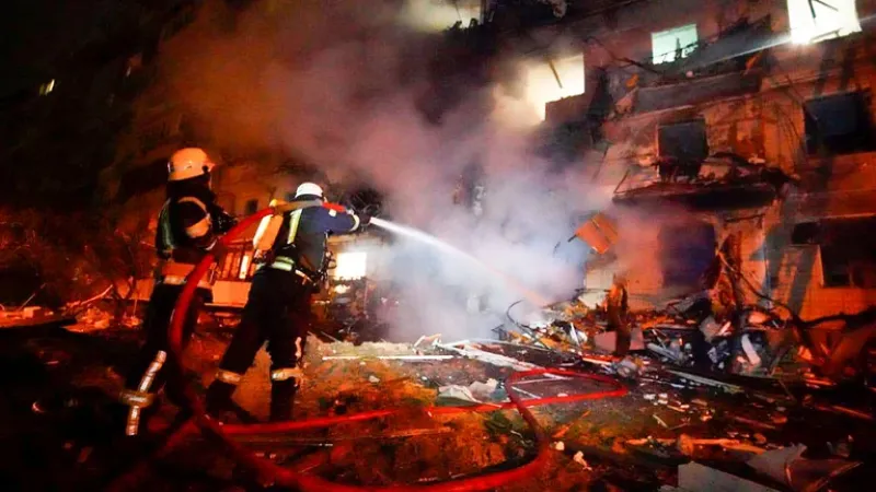 En esta imagen, tomada de un video distribuido por la oficina de prensa del Departamento de Policía de Ucrania el 25 de febrebro de 2022, bomberos intentan apagar unos escombros delante de un edificio en llamas tras un ataque con un misil a la ciudad de K