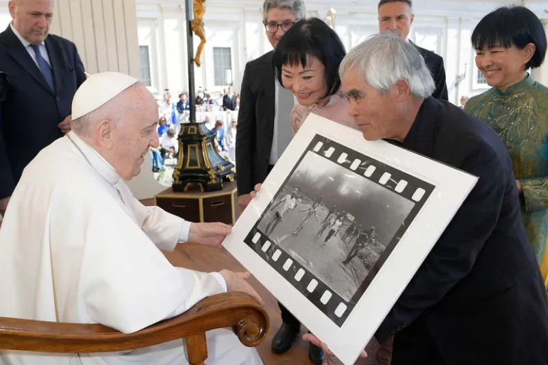  El fotógrafo Nick Ut le muestra al Papa Francisco su foto de 1972 ”El terror de la guerra”, también conocida como la ”Niña del napalm”, junto a Kim Phuc, el11 de mayo de 2022