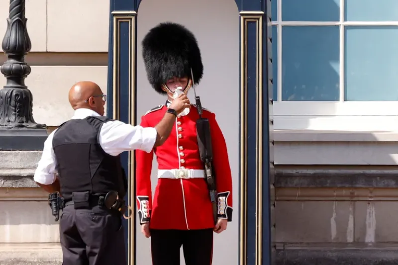 Un miembro de la Guardia de la Reina recibe agua para beber durante la ola de calor, en las afueras del Palacio de Buckingham en Londres