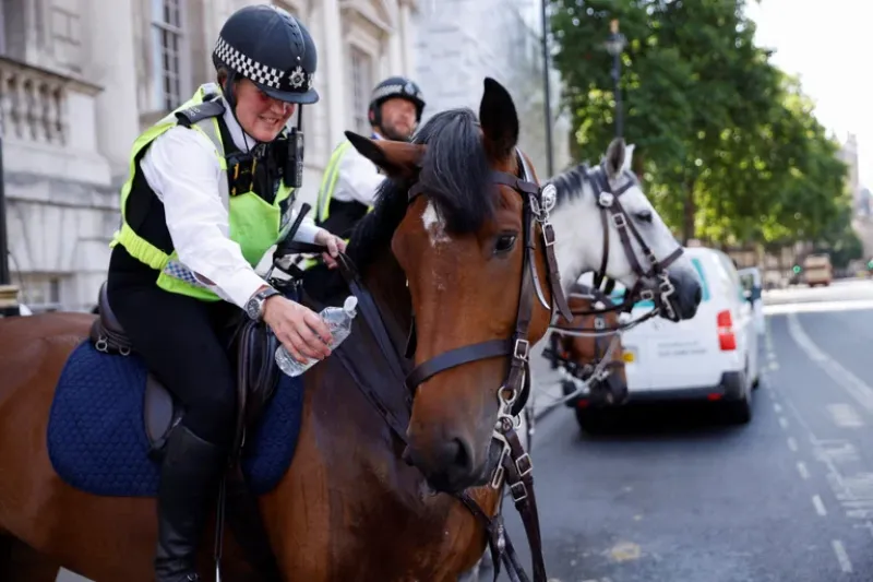 Un oficial de policía ofrece una botella de agua a un caballo de la policía llamado Zack durante el clima caluroso, en Whitehall en Londres, Gran Bretaña, el 18 de julio de 2022