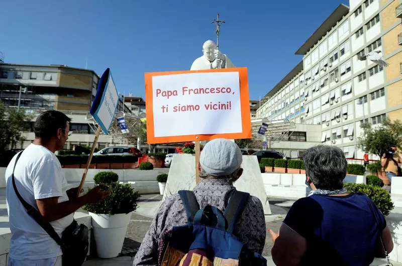 Un grupo de personas porta un cartel con la leyenda ”Papa Francisco, estamos cerca tuyo” frente al Policlinico A. Gemelli de Rome 