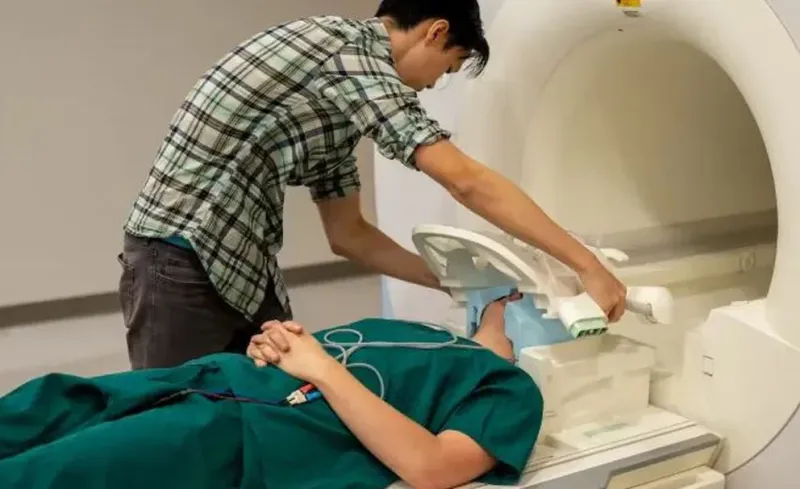 El estudiante Jerry Tang prepara al paciente para recopilar datos de su actividad cerebral dentro del resonador magnético