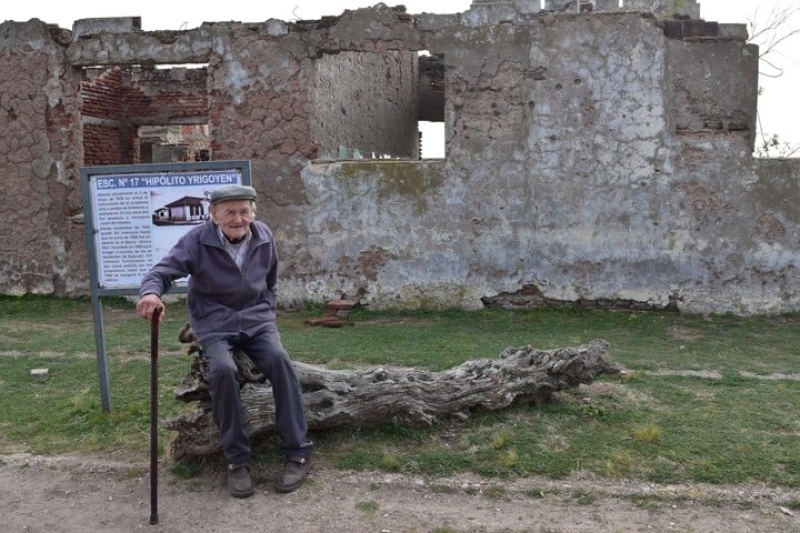 Pablo Novak posando junto a las ruinas de una escuela