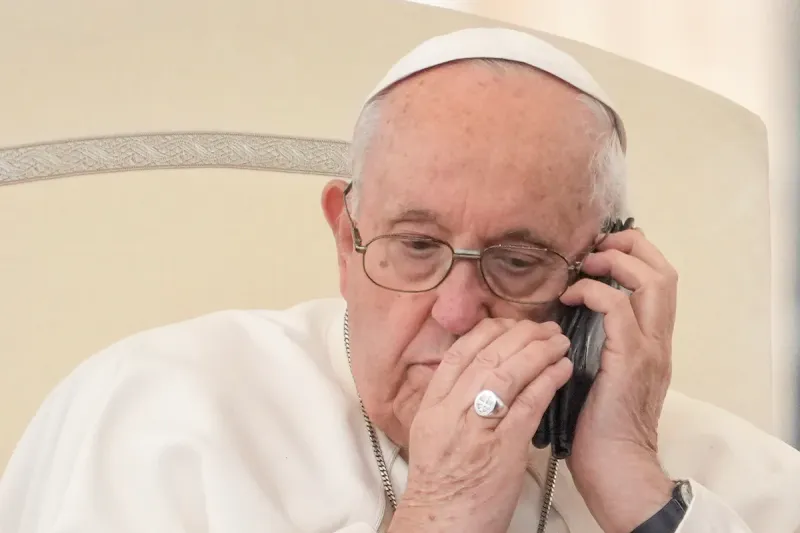 El papa Francisco habla por teléfono durante la audiencia general en San Pedro