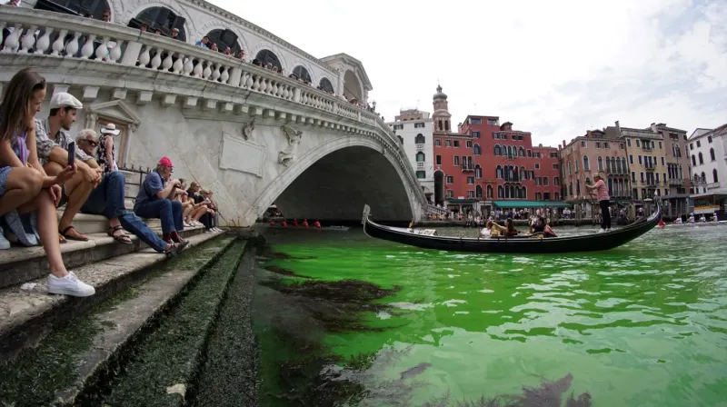 Turistas observan las aguas verdes del Gran Canal de Venecia