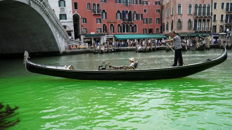 Una tradicional góndola atraviesa el Gran Canal de Venecia, cuyas aguas aparecieron teñidas de verde