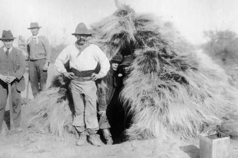  Detrás de uno de los hacheros se alcanza a visualizar las precarias viviendas donde pasaban el escaso tiempo libre (Foto: Archivo histórico provincial)