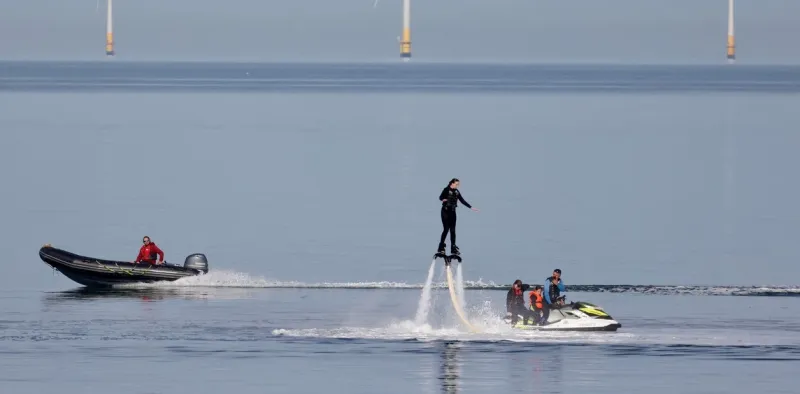 19/31Una lancha pasa a una persona con un flyboard cerca de un parque eólico en un día caluroso en Herne Bay, Gran Bretaña. Foto: REUTERS/Kevin Coombs