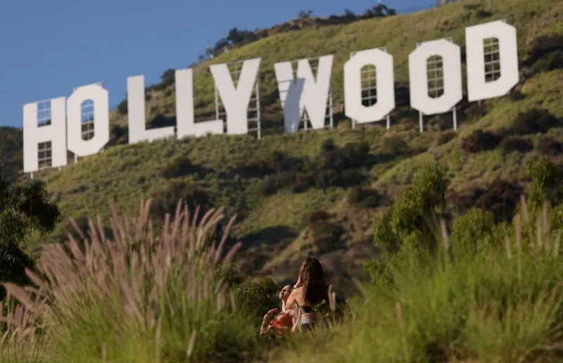 4/31 Una mujer posa junto al icónico cartel de Hollywood el día en que los miembros del Writers Guild of America (WGA) aprobaron un nuevo contrato de tres años con importantes estudios, en los Ángeles, California. Foto: REUTERS/Mario Anzuoni