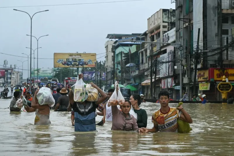 10/31Los residentes cargan sus compras mientras caminan por una calle inundada después de fuertes lluvias en el municipio de Bago en la región de Bago en Myanmar. Foto: SAI AUNG MAIN / AFP