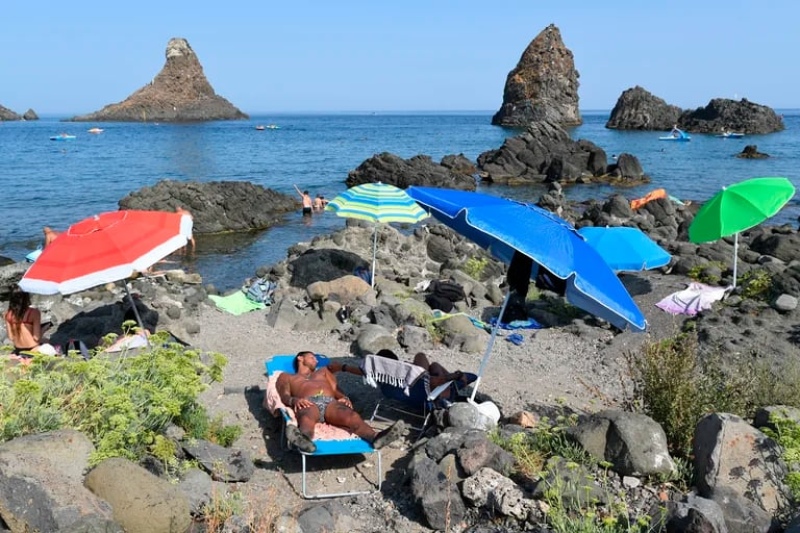  Bañistas disfrutan de un día de playa en Aci Trezza, cerca de Catania, Sicilia, Italia. (AP Foto/Salvatore Cavalli, archivo)