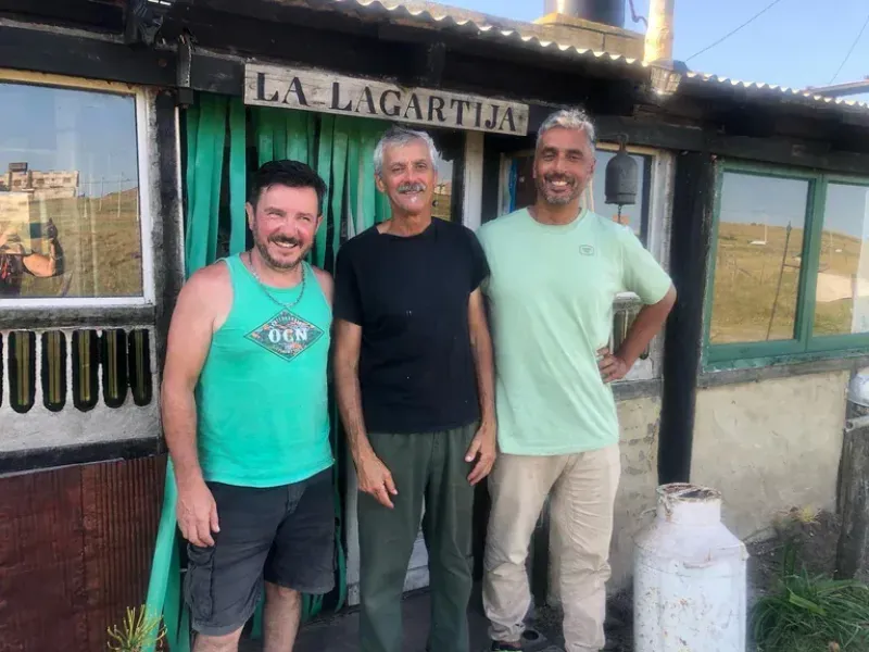 Carlos junto a dos de sus exalumnos, estudiantes en formación de guardavidas, frente a la entrada de la pulpería